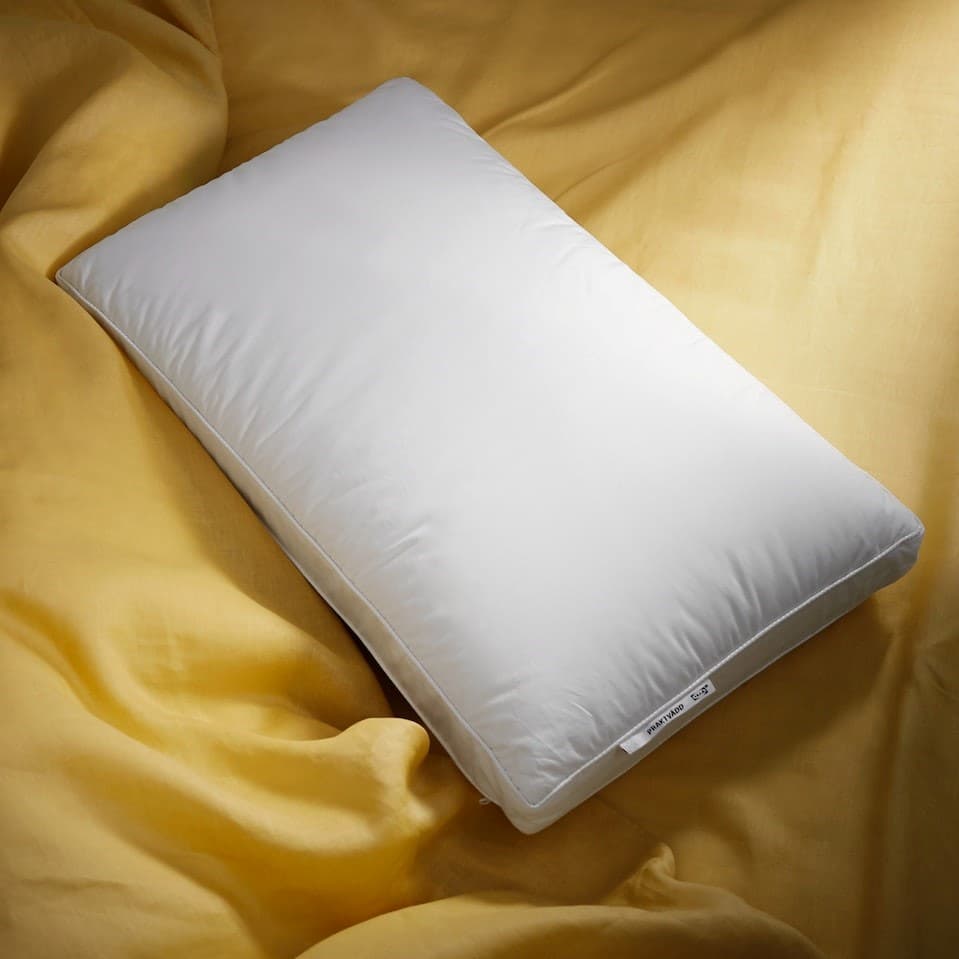 The corner of a green room with a dark wooden bed in it covered in white bed linen and with a man sitting up in it.