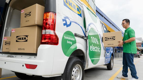 The coworker is loading the parcel into the EV Van, ready to be delivered to the customer's home