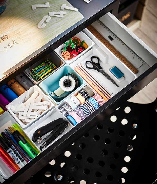The desk drawer is open to reveal lots of organizers and school supplies.
