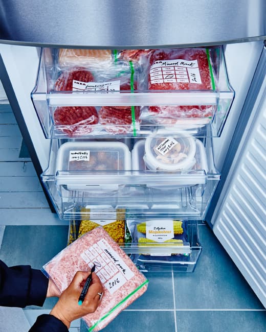 The drawers of a freezer are pulled out to reveal perfectly organized and labeled packages