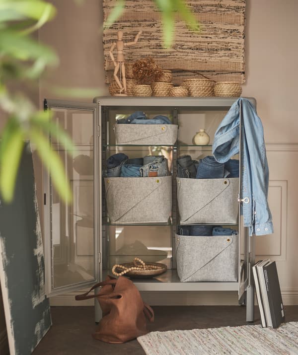 The glass and metal of a FABRIKÖR cabinet is transformed by adding round, handwoven baskets and felt baskets.