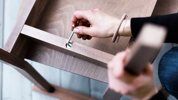 The hand of the person assembling the furniture with an Allen key