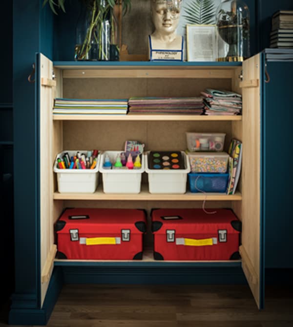 The inside of an cabinet is arranged to organize childrens’ art supplies.