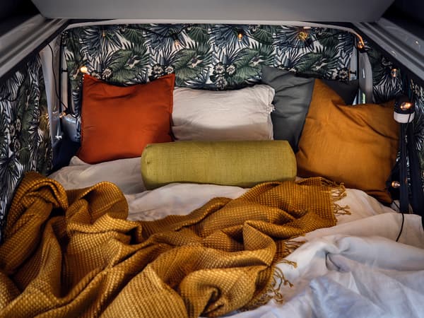 The inside of the van filled with colorful pillows and blankets