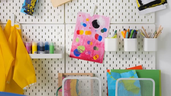 The picture shows an organised craft room with art supplies and a colourful painting.