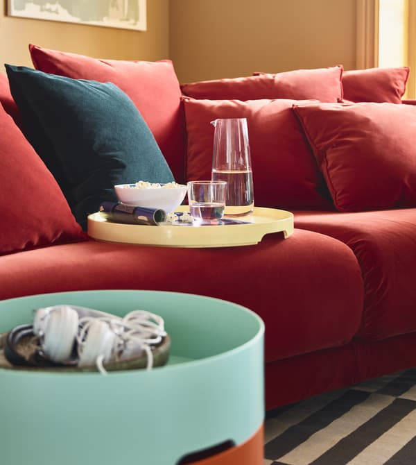 The removable lid of a storage table acts as a tray for snacks and sits on a sofa.