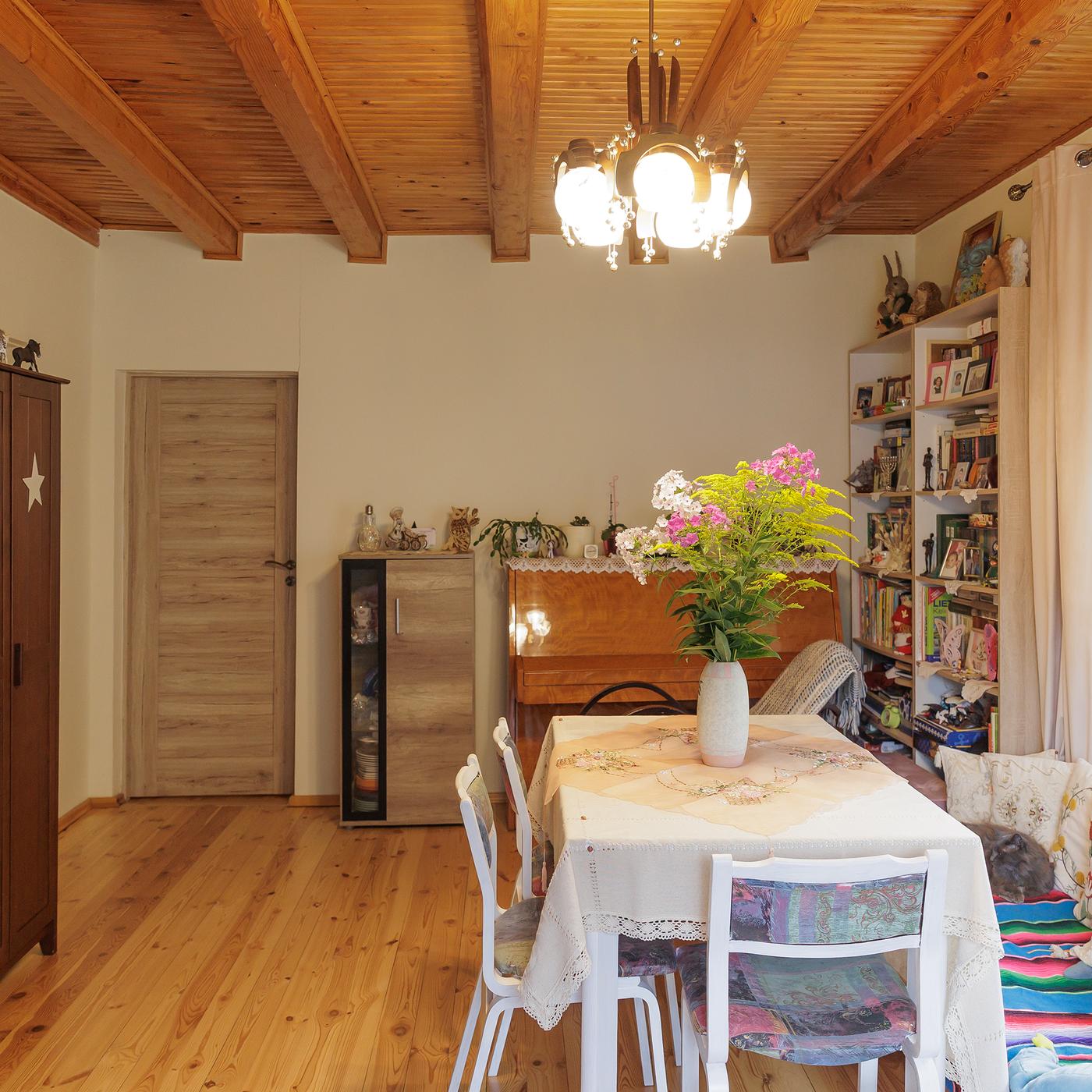The same room from another angle, featuring a dining table with chairs, a piano, a wardrobe, and a cabinet by the door.