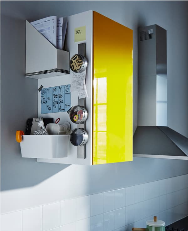 The side of a high kitchen cabinet holds a family schedule, papers and organised odds and ends.