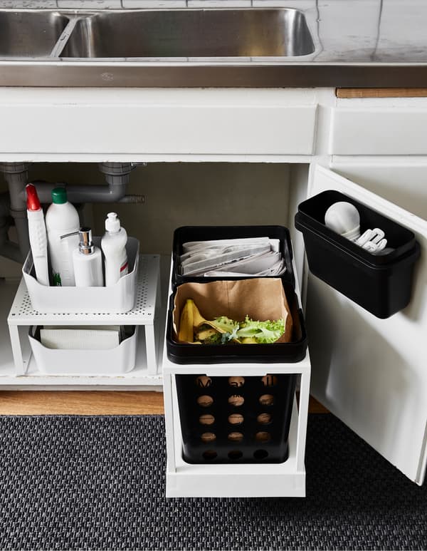 The space under the kitchen sink is updated with new storage that allows waste separation for recycling. On the right side two bins on a movable rail add functionality. To the left a shelf insert doubles storage space.