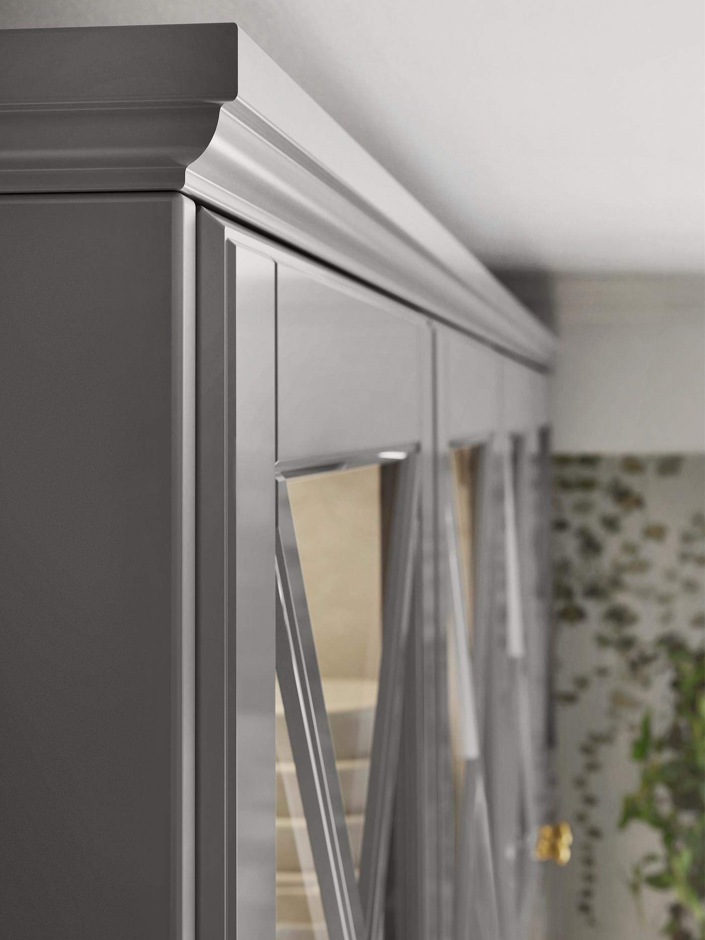 The top corner of a row of grey kitchen cabinets with glass doors and a matching contoured decorative moulding on top.