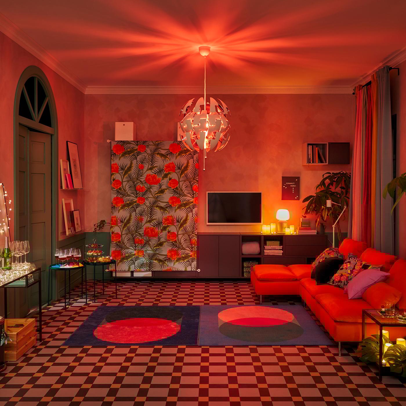 The upper section of a living room, dominated by an IKEA PS pendant lamp bouncing a reddish, club-like glow off the ceiling.