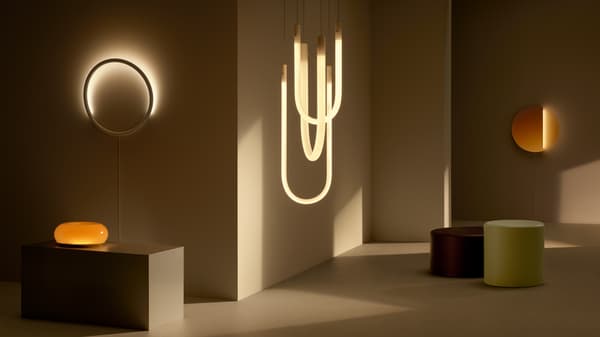 The VARMBLIXT lighting products are switched on in a dim, minimal space with VARMBLIXT coffee tables.