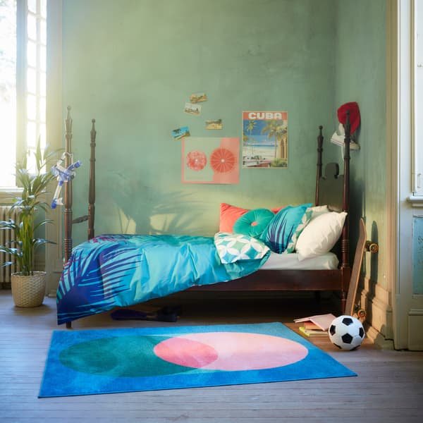 The vibrant GRACIÖS textile series including a quilt cover, cushions and a rug in a bright teenager’s bedroom.