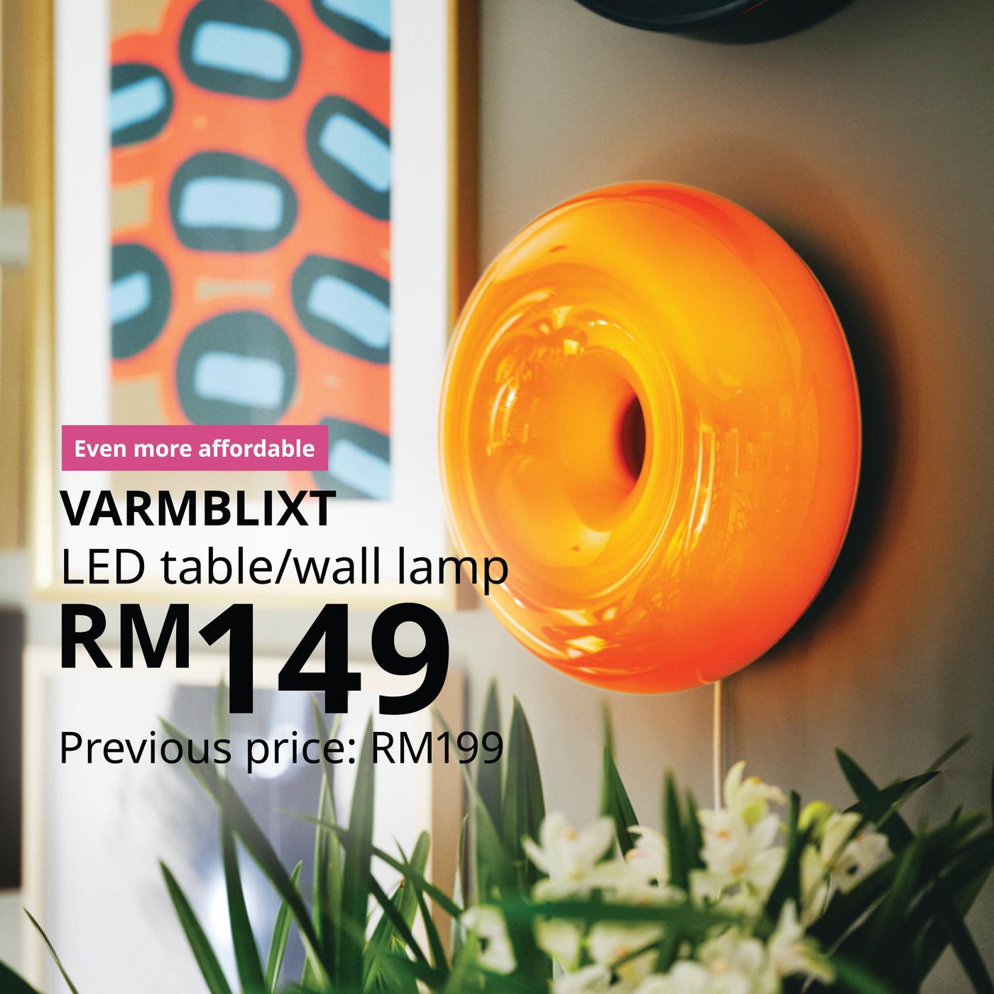 The visual shows an orange VARMBLIXT LED table/wall lamp glowing against a colourful interior setting. The text reads: “Even more affordable. VARMBLIXT LED table/wall lamp, RM149. Previous price: RM199.”