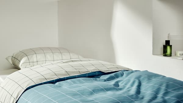 The VITKLÖVER quilt cover is styled on a single bed, folded over to show the different base colour on each side.