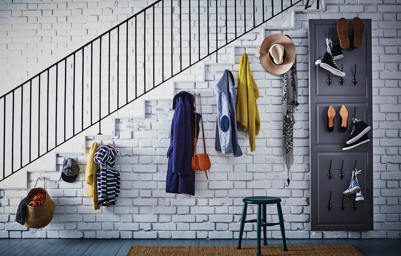 The wall on the side of the stairs with hooks wth coats and hats, and a big mirror as hallway.