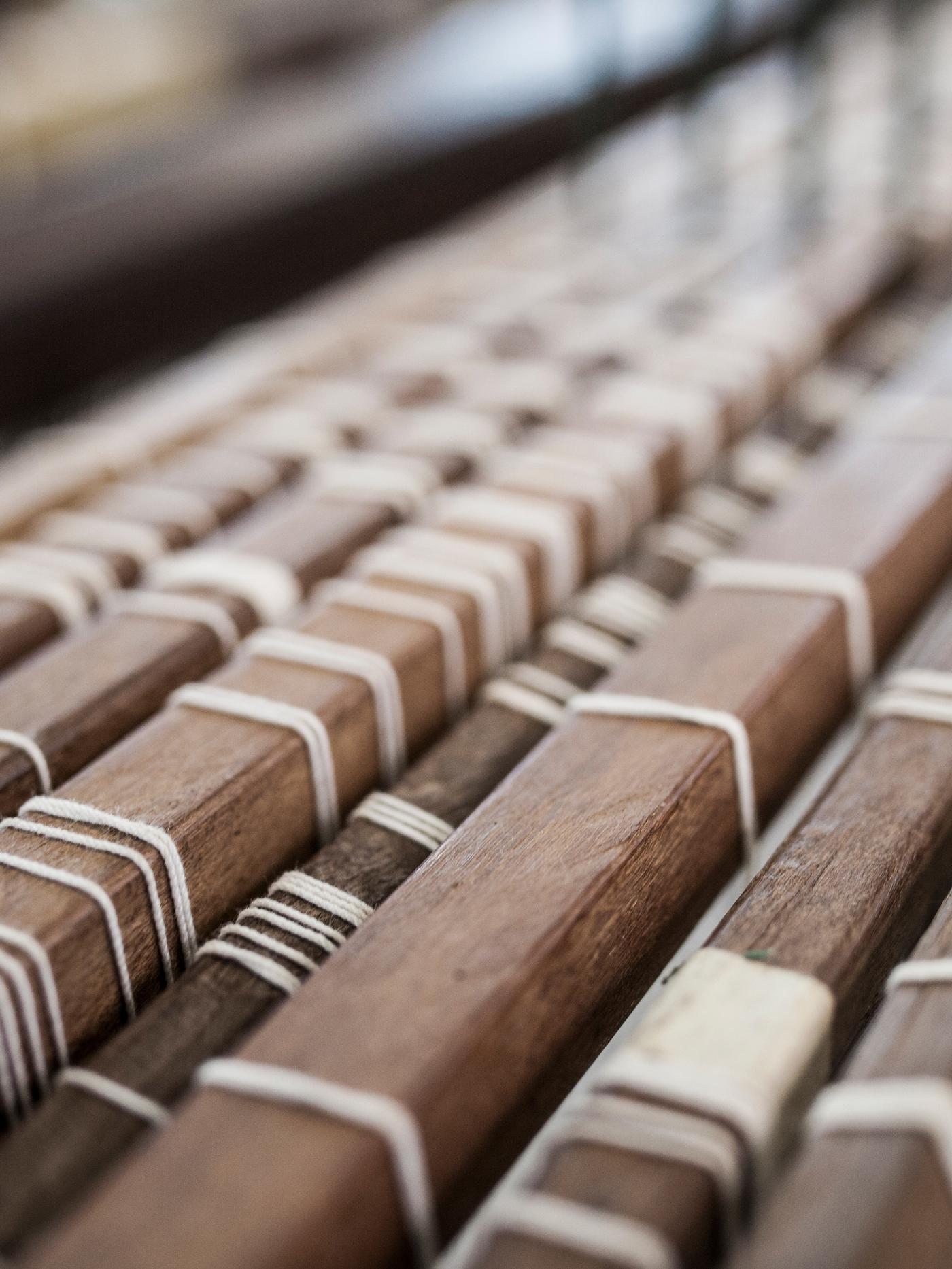 The wooden slats of a weaving loom threaded with white yarn.