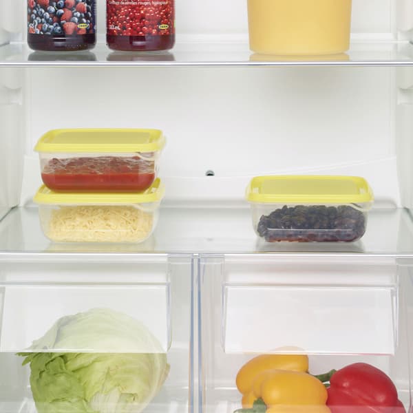 The yellow PRUTA food containers in a fridge with vegtables and fruit.