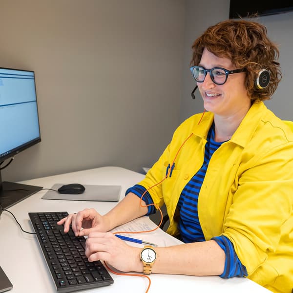The yellow shirt and arms of an IKEA coworker are in focus as they work to help a customer with black hair to design and plan their business.