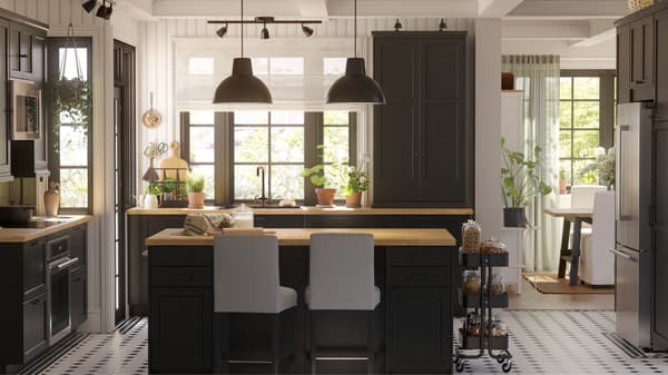 This is a big kitchen with black-stained LERHYTTAN fronts and a kitchen island with two black pendant lamps in the center.