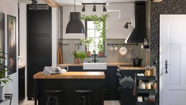 This is a small kitchen with black-stained LERHYTTAN fronts and a kitchen island with a black pendant lamp in the middle.