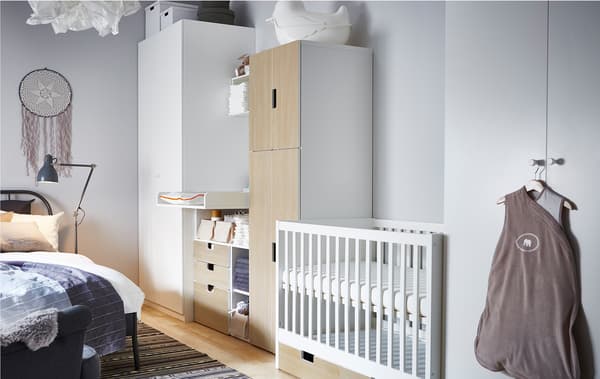 This nursery idea places a cot, changing table and babies storage in between two wardrobes for the parents.