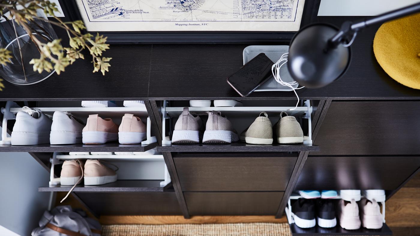 Three black/brown BISSA shoe cabinets with three compartments with several pairs of shoes inside the open compartments.