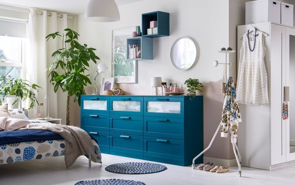 Three bold blue chests of drawers lined up against the wall in a neutral-toned bedroom create an accent piece.