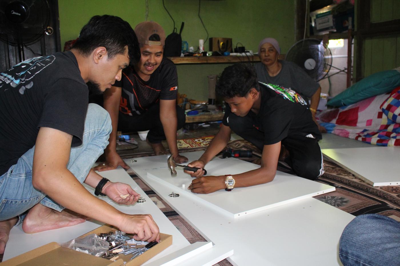 Three co-workers are discussing on how to assemble the furniture