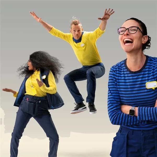 Three IKEA employees in uniform, smiling and energetic, posing and jumping.
