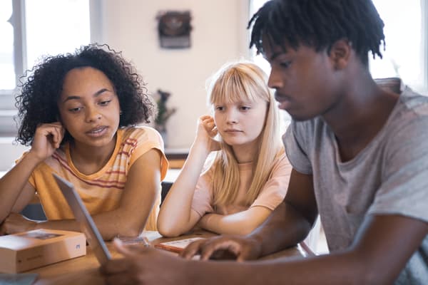 Three kids looking at a laptop screen.