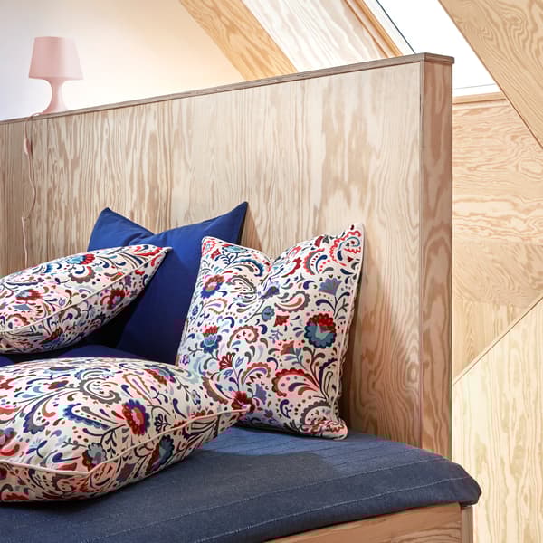 Three KRATTEN cushion covers featuring a floral, Scandinavian traditional pattern in many colours on a white background.