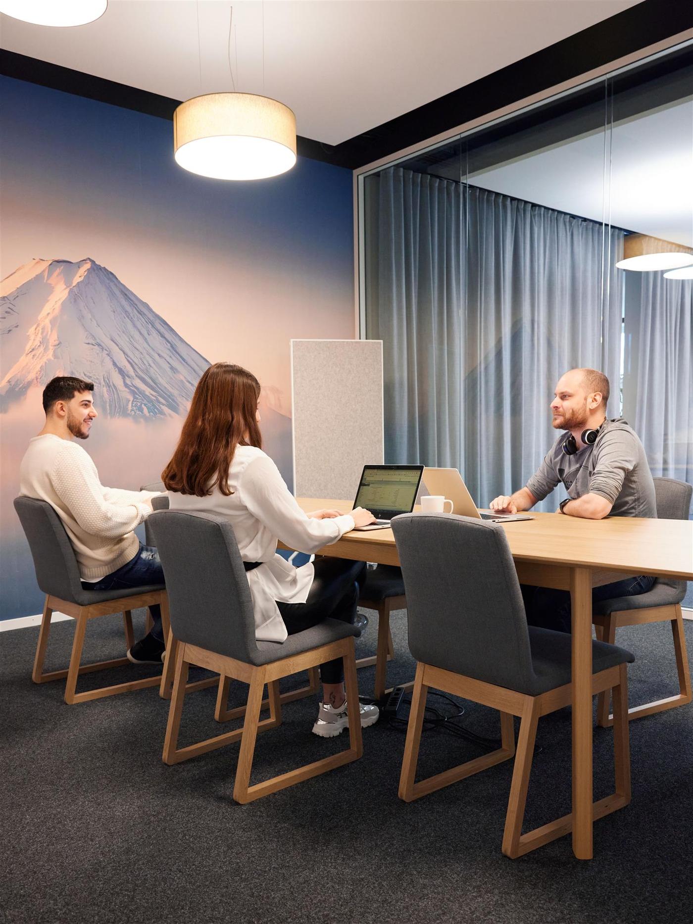 Three people sitting at a desk in a conference room