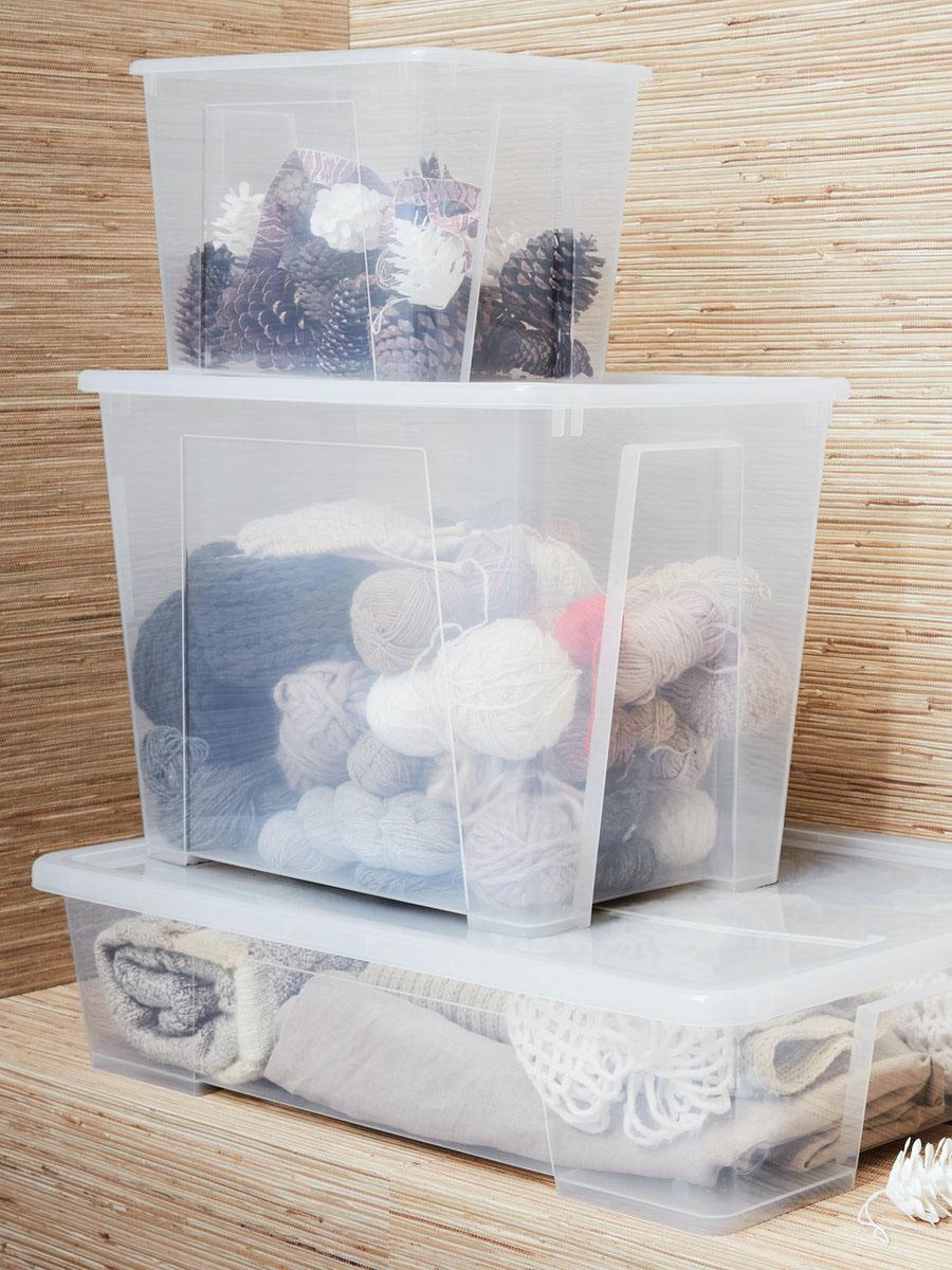 three Samla boxes stacked one on top of the other; a shallow long one, a tall one and a small one filled with clothing, wool and accessories