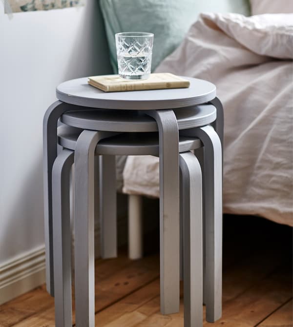Three stacked grey stools are used as a bedside table.