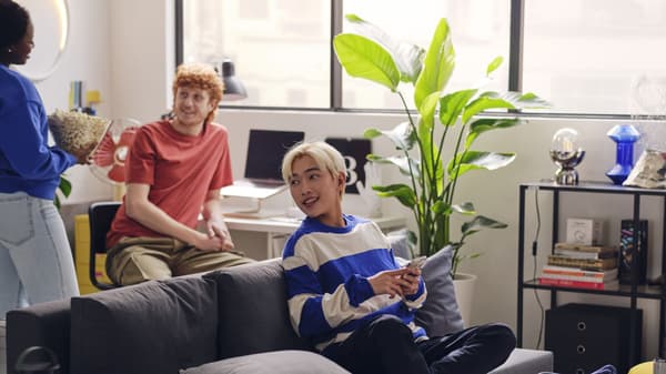 Three students hanging out and talking in the living area of their dorm.