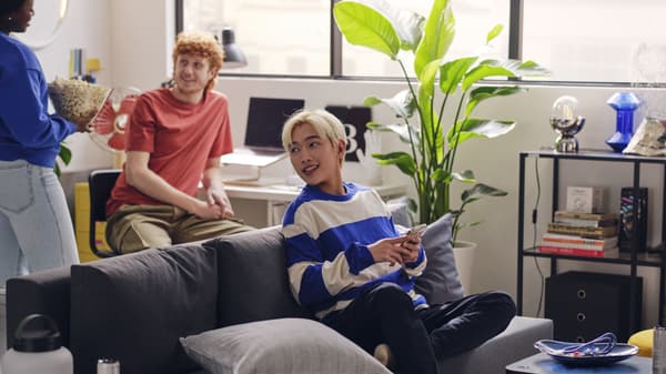 Three students hanging out and talking in the living area of their dorm.