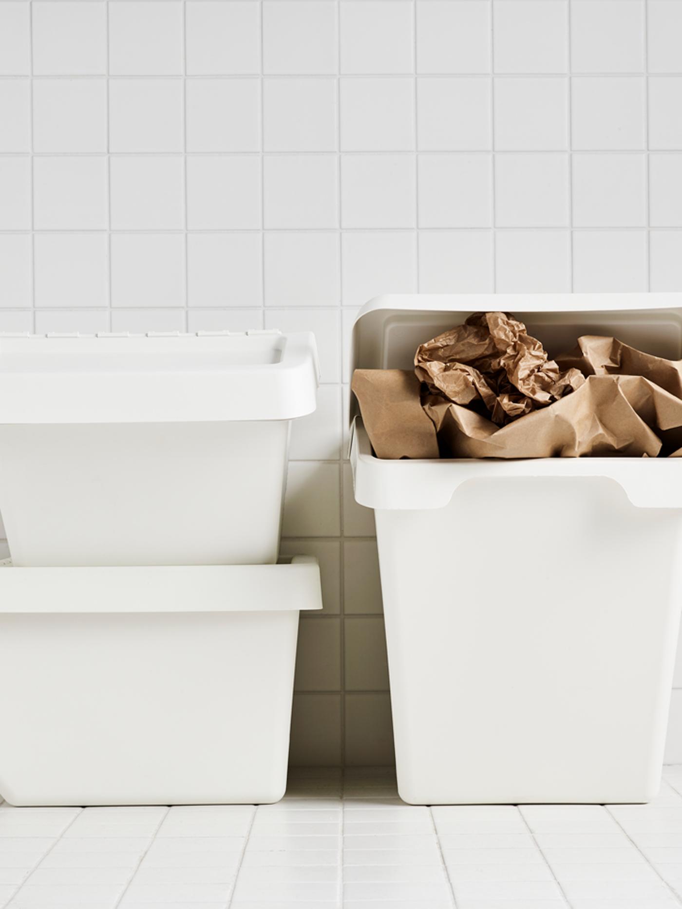 Three white SORTERA bins in a white tiled room where one is stuffed with brown paper.