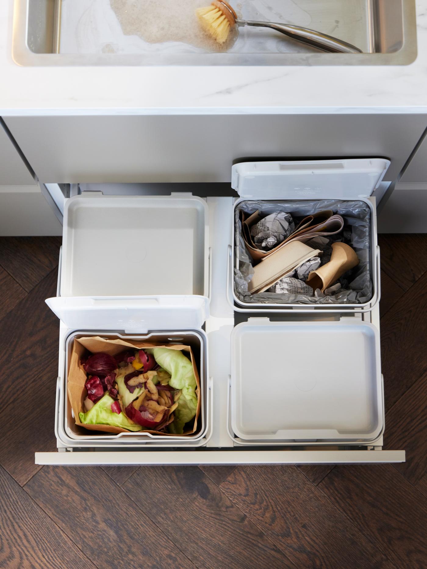 Three white SORTERA bins in a white tiled room with paper waste inside