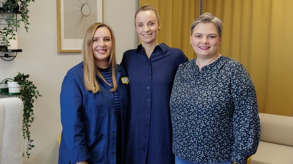 Three women smiling together in modern interior space