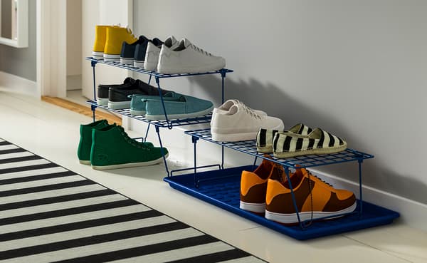 Tiered blue wire shoe rack displays colorful sneakers and boots in a bright hallway, creating an organized, stylish entryway beside a striped rug.