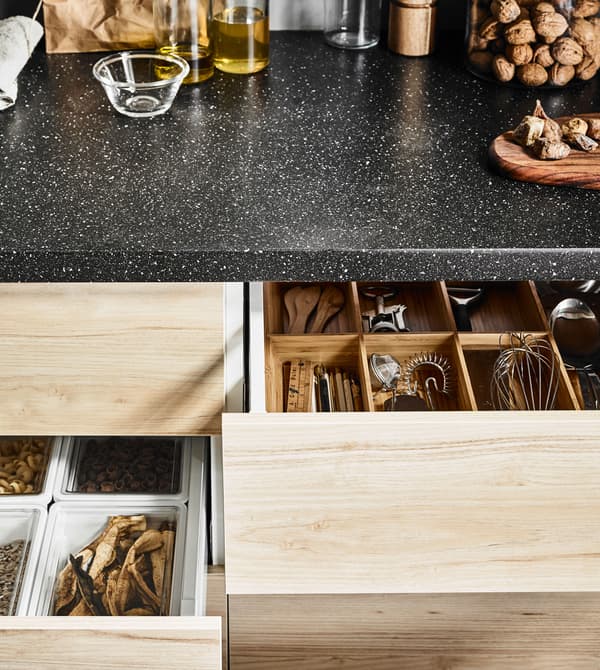 Tiroir de cuisine profond avec façade en frêne, ouvert, avec casseroles et couvercles bien rangés.