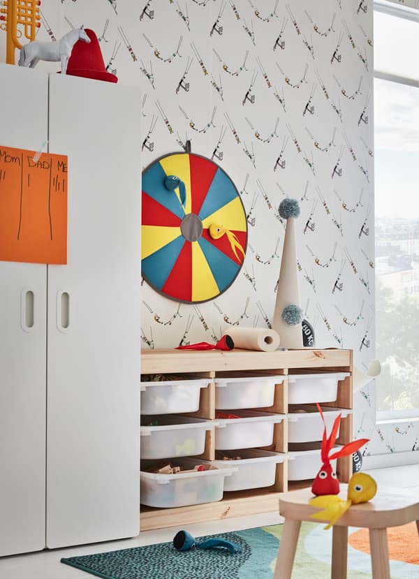 Tiroirs en pin et plastique blanc IKEA TROFAST et jeu de fléchettes LUSTIG, un deux-en-un pour permettre aux enfants à la fois de ranger et jouer. Légères, les pieuvres en peluche sont faciles à lancer sur la cible.