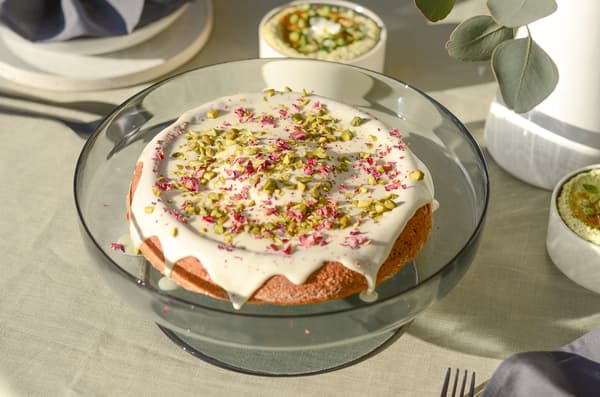 Tisch mit Kuchen, Dips, Brot, Wassergläsern, Besteck, Servietten und Vasen mit Trockenblumen und Eukalyptus.