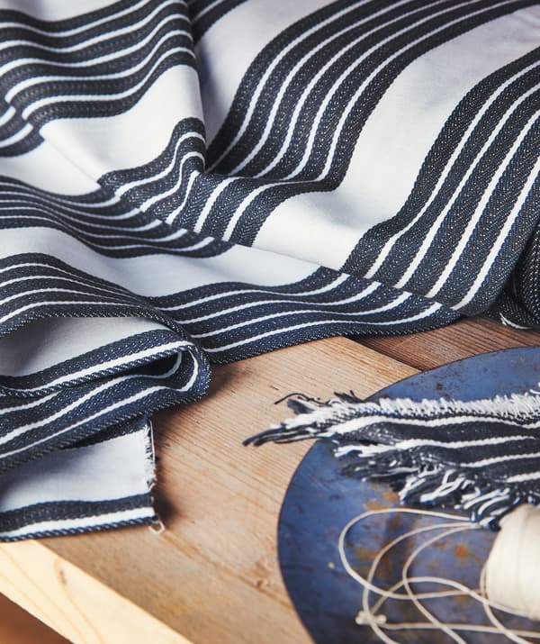 Tissu à rayures bleu et blanc et un plateau bleu sur un plateau de table en bois.