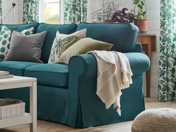 ターコイズブルーのソファを置いたリビング。柄入りカーテンとクッションで爽やかな印象。