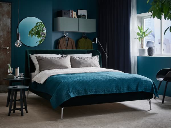 ターコイズのベッドに白い寝具を合わせたスタイリッシュな寝室。濃いブルーの壁で高級感を演出。