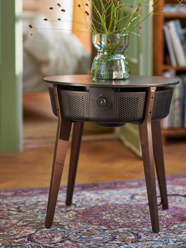 Tmavohnedý stolík s čističkou vzduchu STARKVIND na koberci s perzským vzorom.