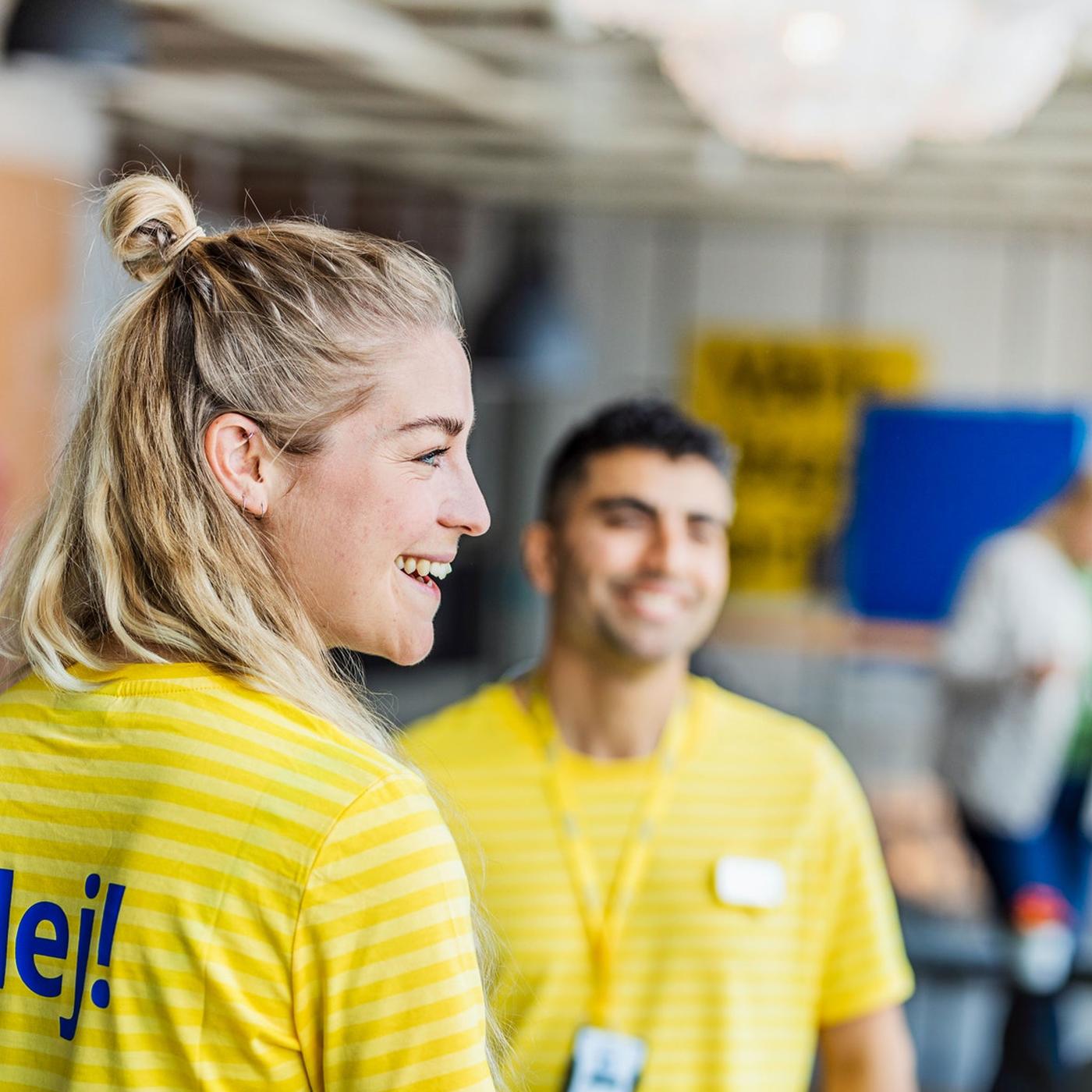 To IKEA ansatte i gule t.-skjorter smiler og ler.