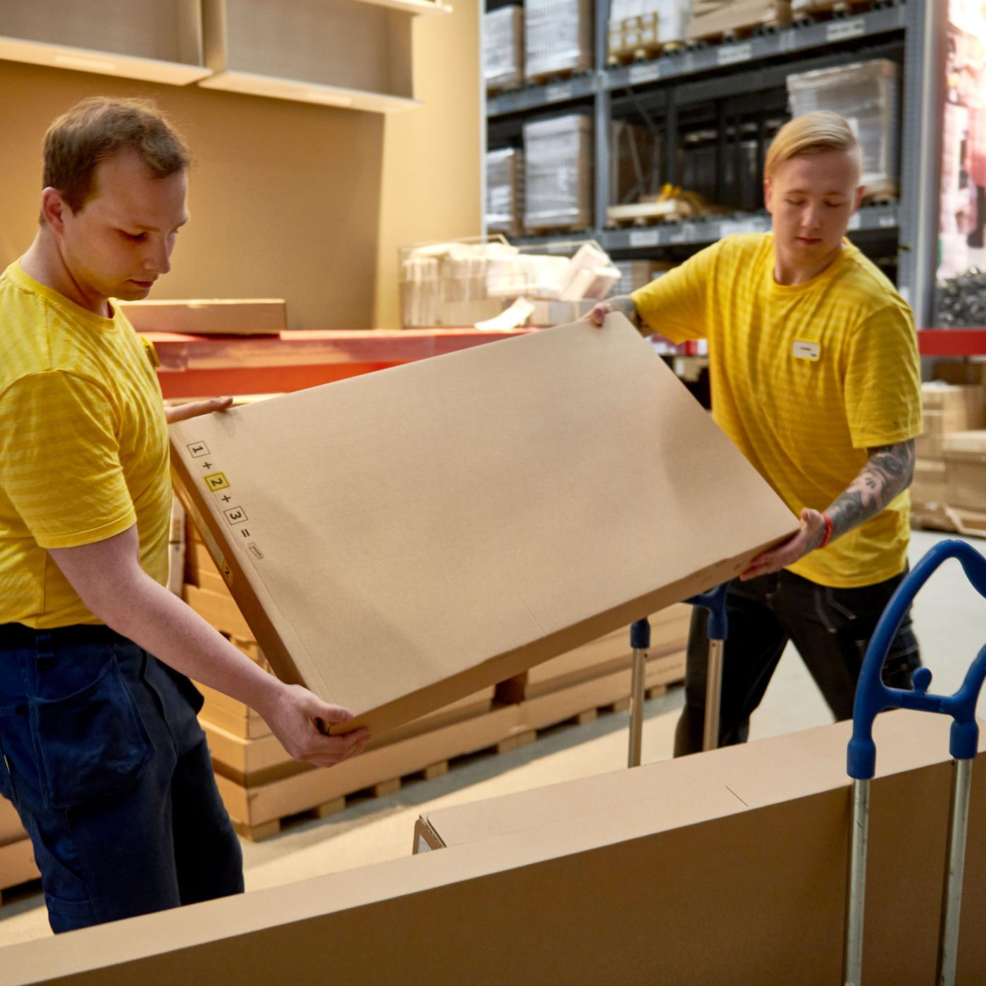 To IKEA ansatte laster en tralle med flatpakker. 